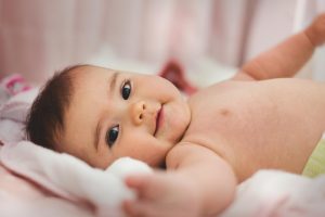 smiling baby lying on a pink bed